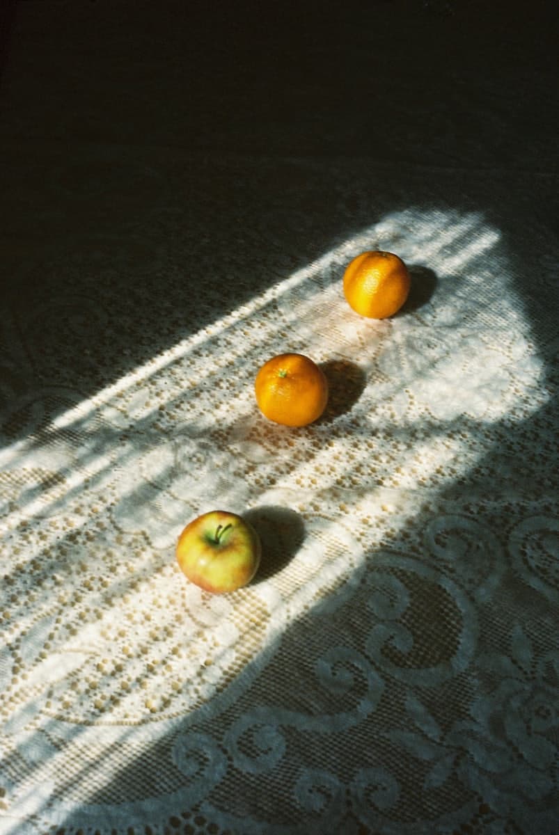 Fresh fruit resting in warm morning sunlight on a lace tablecloth